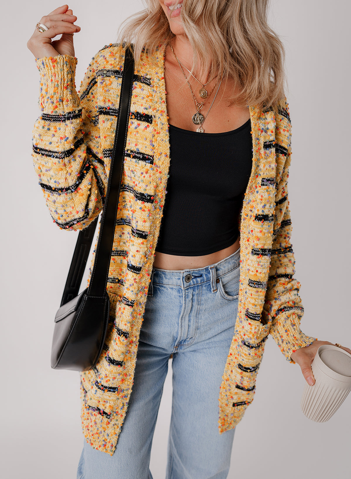 Cardigan long rayé en tricot a pompons ouvert sur le devant
